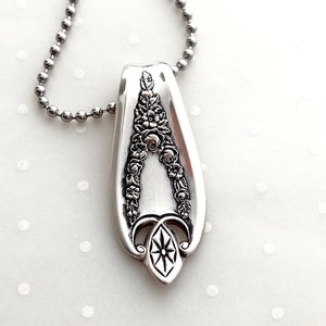 May include: A silver necklace with a floral design pendant made from a repurposed spoon.