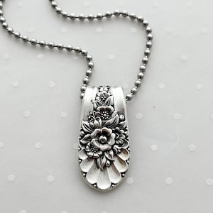 May include: A silver necklace with a floral pendant made from a repurposed spoon. The pendant features a detailed floral design with a central rose.
