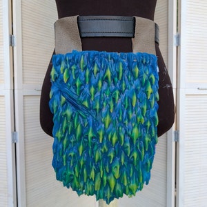 May include: A blue and green leather belt pouch with a scaly texture. The pouch is attached to a brown leather belt with a black buckle.