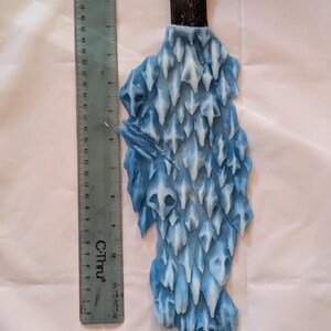 May include: A blue and white ice sculpture with a brown leather handle. The sculpture is shaped like a jagged, pointed rock formation.