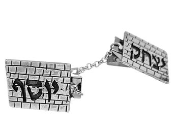 May include: A silver charm bracelet with two rectangular charms. Each charm features a brick pattern and the Hebrew word "ירושלים" (Jerusalem) in black lettering.