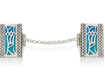 May include: A pair of silver cufflinks with a blue enamel design. The cufflinks are connected by a silver chain.