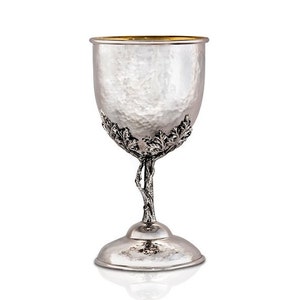 May include: A silver goblet with a hammered finish and a gold rim. The stem is shaped like a tree branch with leaves.