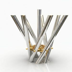 Può includere: Una scultura astratta moderna con tubi in metallo argentato lucido disposti a raggiera. I tubi convergono su una base esagonale dorata, con piccoli accenti dorati. La scultura ha una superficie riflettente ed è su sfondo bianco.