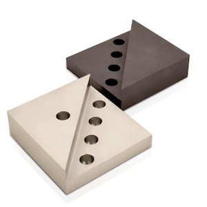 May include: Two square metal blocks with a diagonal cut-out. The top block is dark gray and the bottom block is light gray. Both blocks have circular holes cut into the surface.