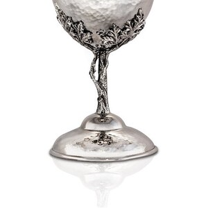 May include: Silver goblet with a hammered finish and a tree branch design. The goblet has a wide base and a round bowl.