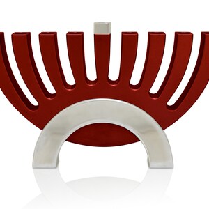 May include: A red menorah with a silver base. The menorah has nine candle holders and a shamash in the center.