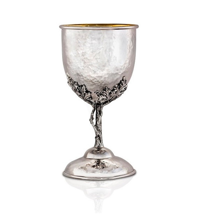 May include: A silver goblet with a hammered finish and a gold rim. The stem is shaped like a tree branch with leaves.