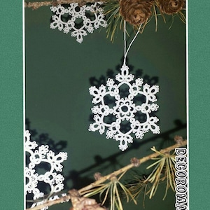 May include: Three white crocheted snowflakes hanging from a pine branch with brown pine cones. The background is a dark green.