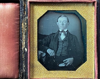 Early sixth-plate daguerreotype  of a young man holding a book. Full case.