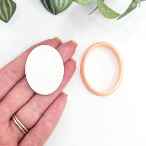 May include: A white round coaster with a speckled texture and a peach-colored round coaster.