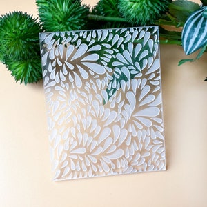 May include: A clear acrylic stamp featuring a white design of abstract teardrop shapes. The stamp is ideal for creating unique patterns on paper, fabric, or other surfaces.