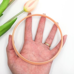 May include: A peach-colored plastic headband with a smooth, rounded surface.