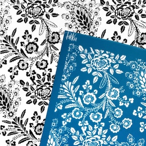 May include: A close-up of a white and black floral pattern fabric next to a blue surface with a white floral design. The blue surface has the word "Paku" in the corner. The floral patterns include roses and other flowers.