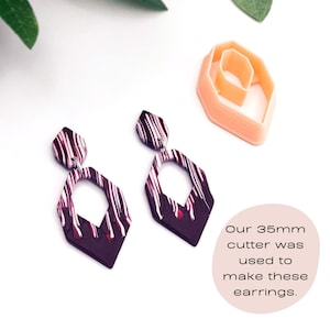 May include: A pair of dark purple and white striped geometric earrings with a 35mm cutter used to make them. "Our 35mm cutter was used to make these earrings."