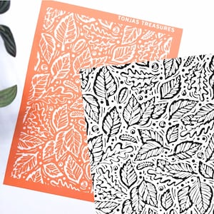 May include: Two rectangular sheets featuring a repeating leaf pattern. One sheet is orange with white leaf outlines, and the other is white with black leaf outlines. The text TONJAS TREASURES is printed in white on the orange sheet.