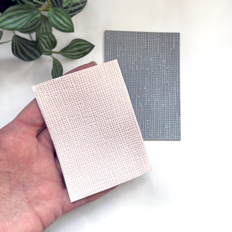 May include: Two textured rubber stamps, one gray and one white, with a grid pattern. The stamps are used for creating embossed designs on paper or other surfaces.