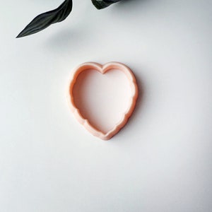 Op de afbeelding: Een roze plastic koekjesvormpje in de vorm van een hart.