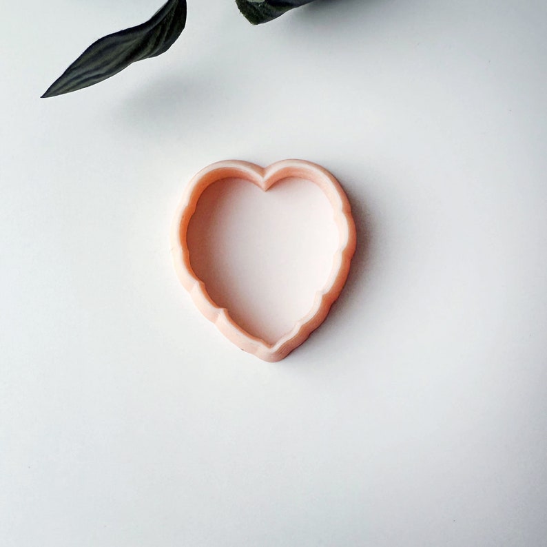 Op de afbeelding: Een roze plastic koekjesvormpje in de vorm van een hart.