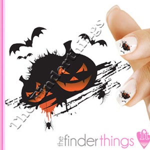 May include: Halloween nail art stickers featuring black silhouettes of pumpkins with orange faces and bats flying around them. The stickers are on a white background with black splatters and spiders.