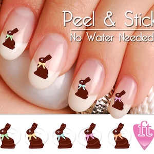 May include: Chocolate bunny nail stickers with pastel colored bows. Peel and stick, no water needed.  The image shows a hand with four fingers, each with a different colored bow on the chocolate bunny.