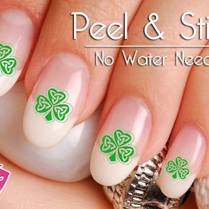 May include: Green shamrock nail decals with a Celtic knot design. The decals are shown on fingernails and the text "Peel & Stick No Water Needed" is visible.