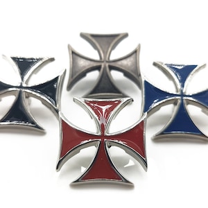 Puede incluir: Cuatro cruces de Malta de metal con incrustaciones de esmalte de diferentes colores. Las cruces son negras, plateadas, azules y rojas.