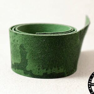 May include: A roll of dark green leather, rolled up and ready to be used for crafting projects. The leather is a natural material with a slightly textured surface.
