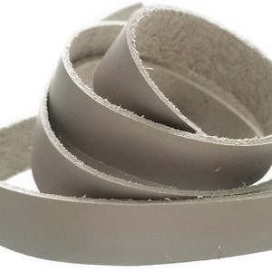 May include: A roll of light gray leather strap, approximately 1 inch wide, with a rough, unfinished edge.