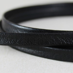 May include: Black leather cord, close-up view showing the texture of the leather.