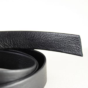May include: Close-up of a black leather strap, showing the textured surface and the edge of the strap.