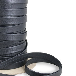 May include: A spool of black leather cord, wound tightly. The cord is smooth and has a slight sheen. The cord is approximately 1.25 cm wide.