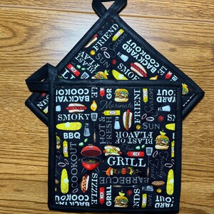 May include: Three black and white pot holders with a BBQ theme. The pot holders feature a variety of images including hot dogs, corn on the cob, and grilling tools. The text on the pot holders includes "BBQ", "Grill", "Backyard Cookout", "Friends", and "Season".