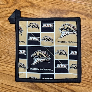 May include: Square pot holder with a black border and a loop for hanging. The design features a repeating pattern of black and tan squares with the Western Michigan Broncos logo and "WMU" text.