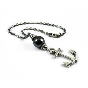 May include: A silver chain necklace with a black bead and a silver anchor charm.
