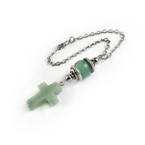 May include: A silver chain with a green stone bead and a green stone cross pendant.