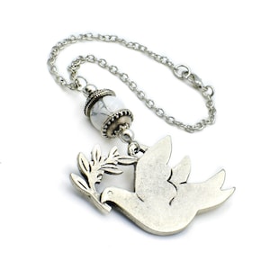May include: A silver peace dove charm with an olive branch and a white marble bead on a silver chain.