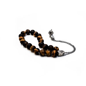 K&ouml;nnte beinhalten: Eine braune und goldene Tigerauge-Perlenmala mit einem silbernen Anh&auml;nger und einer silbernen Kette.