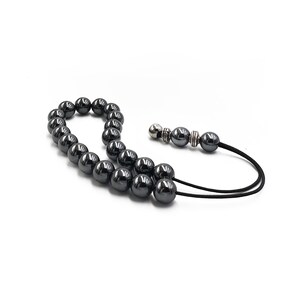 Puede incluir: Un collar de cuentas de oraci&oacute;n mala de hematita negra con un cord&oacute;n negro y detalles plateados.