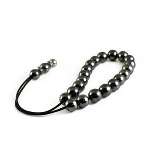 Puede incluir: Un collar de cuentas negras con un cierre plateado. Las cuentas son redondas y lisas, y el collar est&aacute; enhebrado en un cord&oacute;n negro.