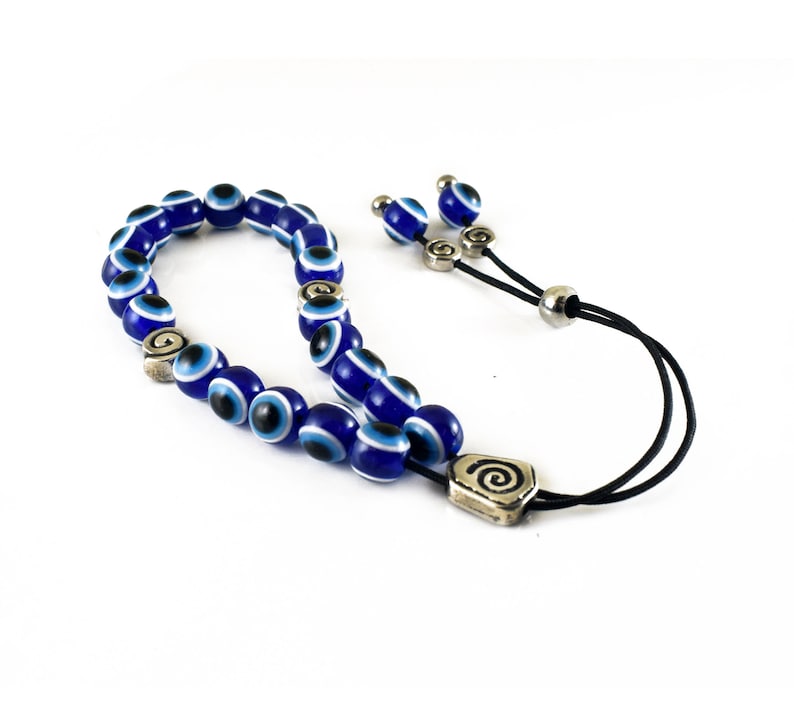May include: A blue and white evil eye bead bracelet with a silver charm. The bracelet is made of a string of beads with a silver clasp.