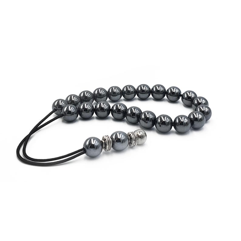 Puede incluir: Un collar mala de cuentas de hematites negras con un borla de plata. Las cuentas son redondas y tienen un acabado liso y pulido.