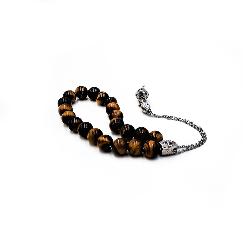 K&ouml;nnte beinhalten: Eine braune und goldene Tigerauge-Perlenmala mit einem silbernen Anh&auml;nger und einer silbernen Kette.