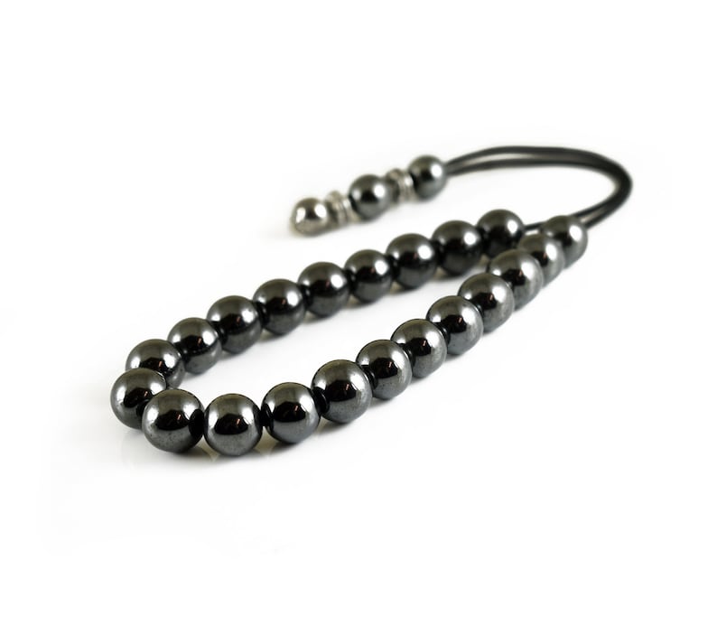 Puede incluir: Un collar de cuentas de hematites negras con un cierre plateado y un cord&oacute;n negro.