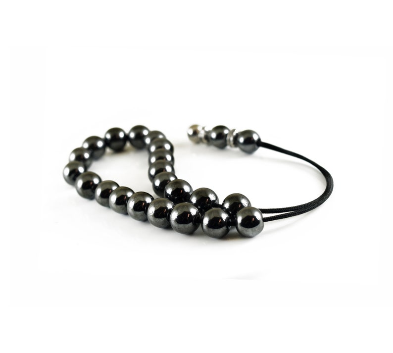 Puede incluir: Un collar mala de cuentas de hematites negras con un cierre plateado y un cord&oacute;n negro.