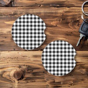 May include: Two round car coasters with a black and white checkered pattern. The coasters are made of a durable material and designed to fit in a car's cup holder. A set of car keys is also visible.