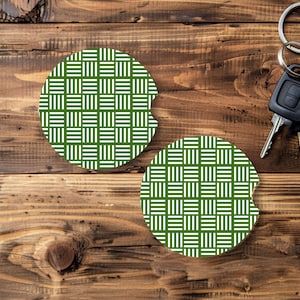 May include: Two round car coasters with a green and white woven pattern. The coasters are on a wooden surface, next to a set of car keys.