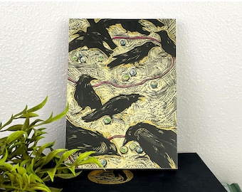May include: A wooden art piece featuring a flock of black crows against a textured, golden-yellow background. The artwork includes red lines and small, round, blue and green accents. The crows are depicted in various poses.