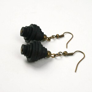 May include: A pair of black dangle earrings with a spiral design and bronze hooks.