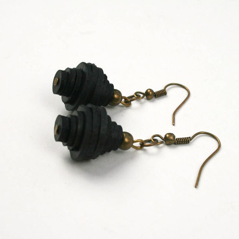 May include: A pair of black dangle earrings with a spiral design and bronze hooks.